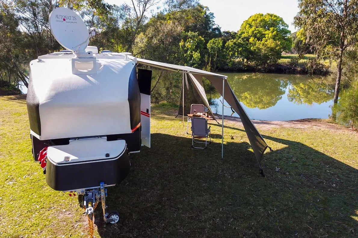 Kruiser T-Class set up with awning out beside a quiet lakeside camp