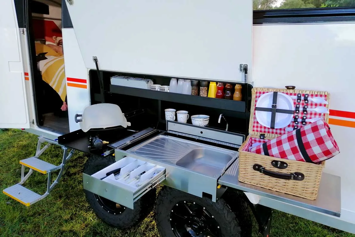 Slide-out external kitchen with sink, cooktop and storage