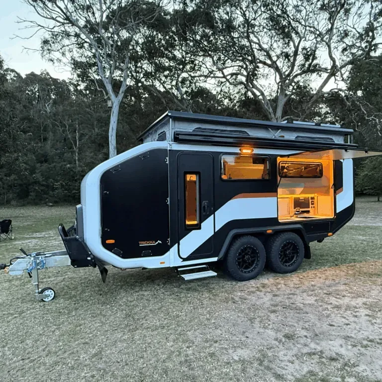 Stockman Trekka set up at a bush campsite at dusk with awning out and interior lit