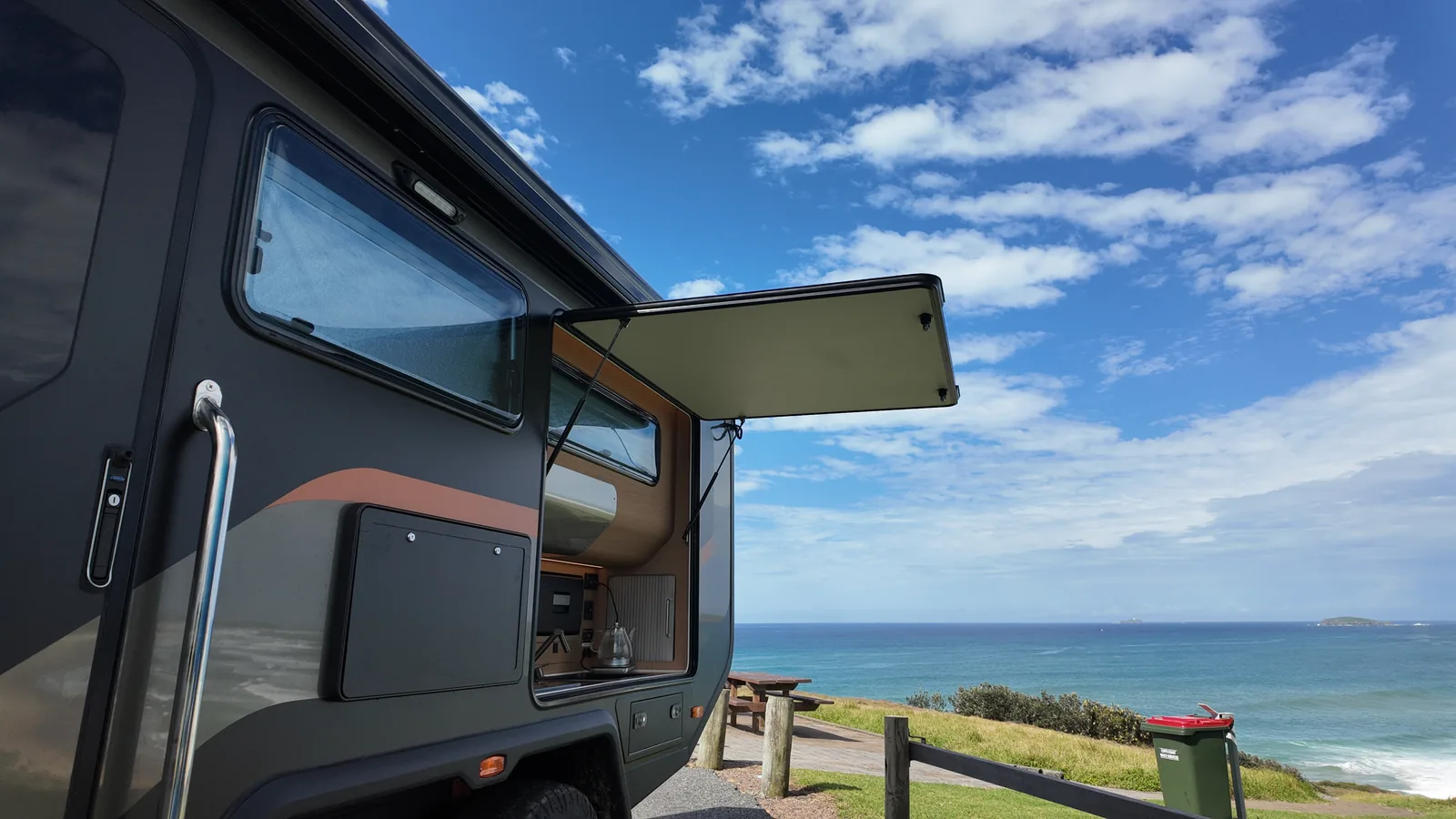 Trekka camped on a coastal headland with hatch open and ocean view