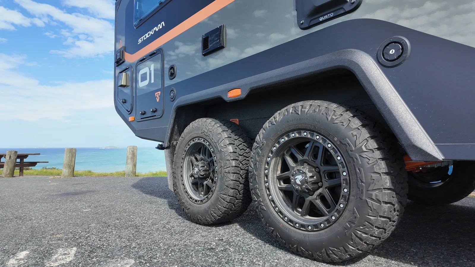 Close-up of the Trekka's all-terrain tyres and tandem off-road suspension by the coast